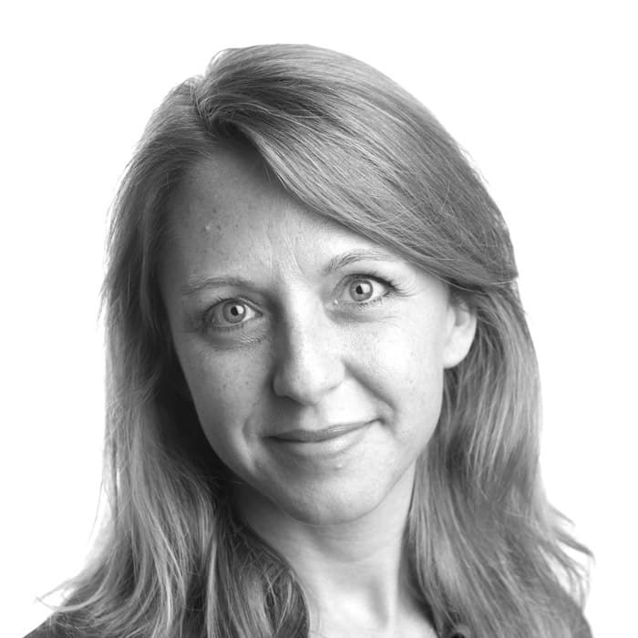 Black and white portrait of a woman with long, straight hair. She is smiling softly and looking directly at the camera, with a neutral background.