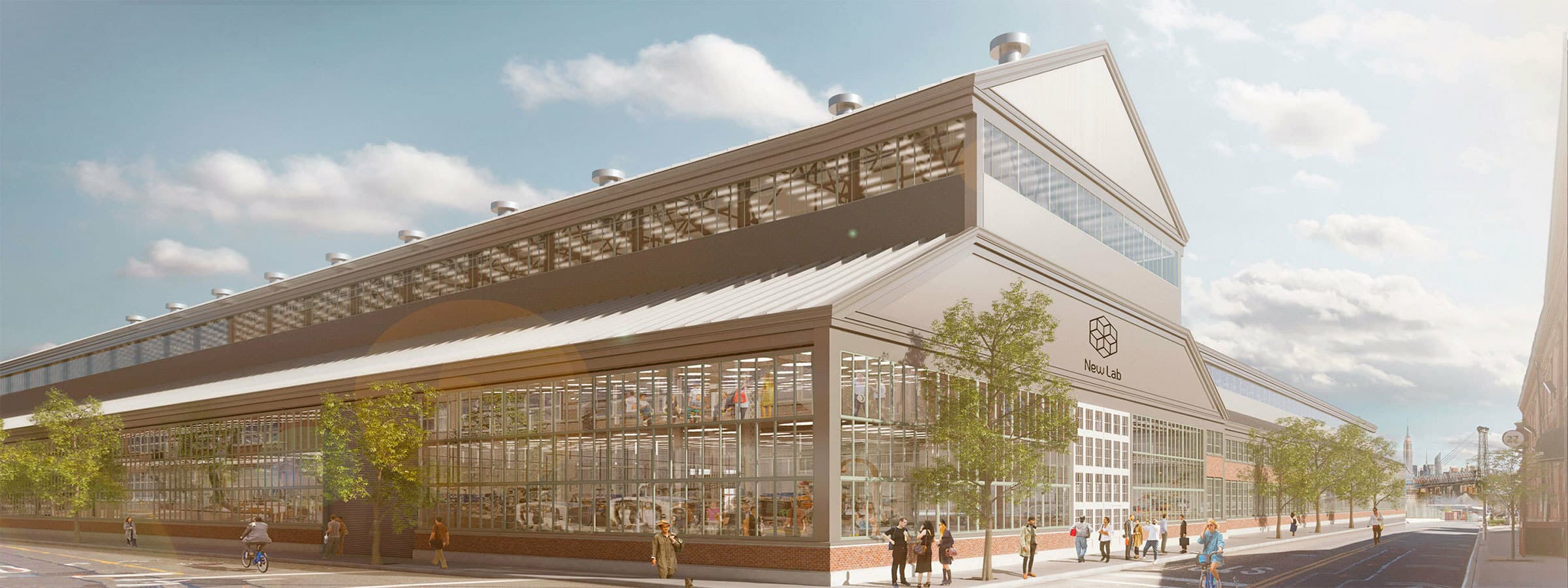 A modern industrial building with large glass windows and a metallic roof on a sunny day. The structure is labeled "New Lab" and features a blend of contemporary and industrial design elements. People are walking and cycling near the building, lined with small trees.