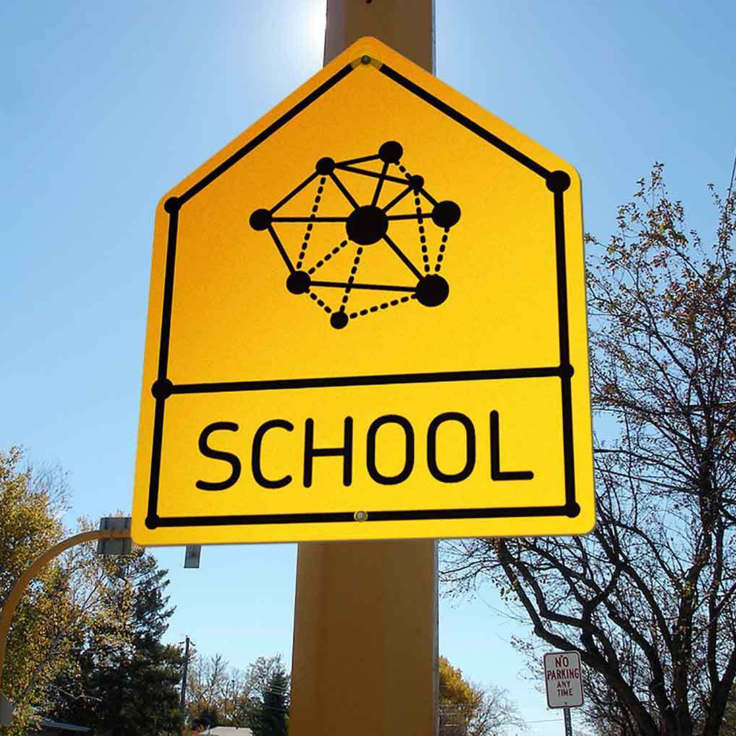 A yellow, pentagon-shaped school zone sign with an abstract design of connected dots forming a network above the word "SCHOOL" in black, mounted on a post with trees and a clear sky in the background.