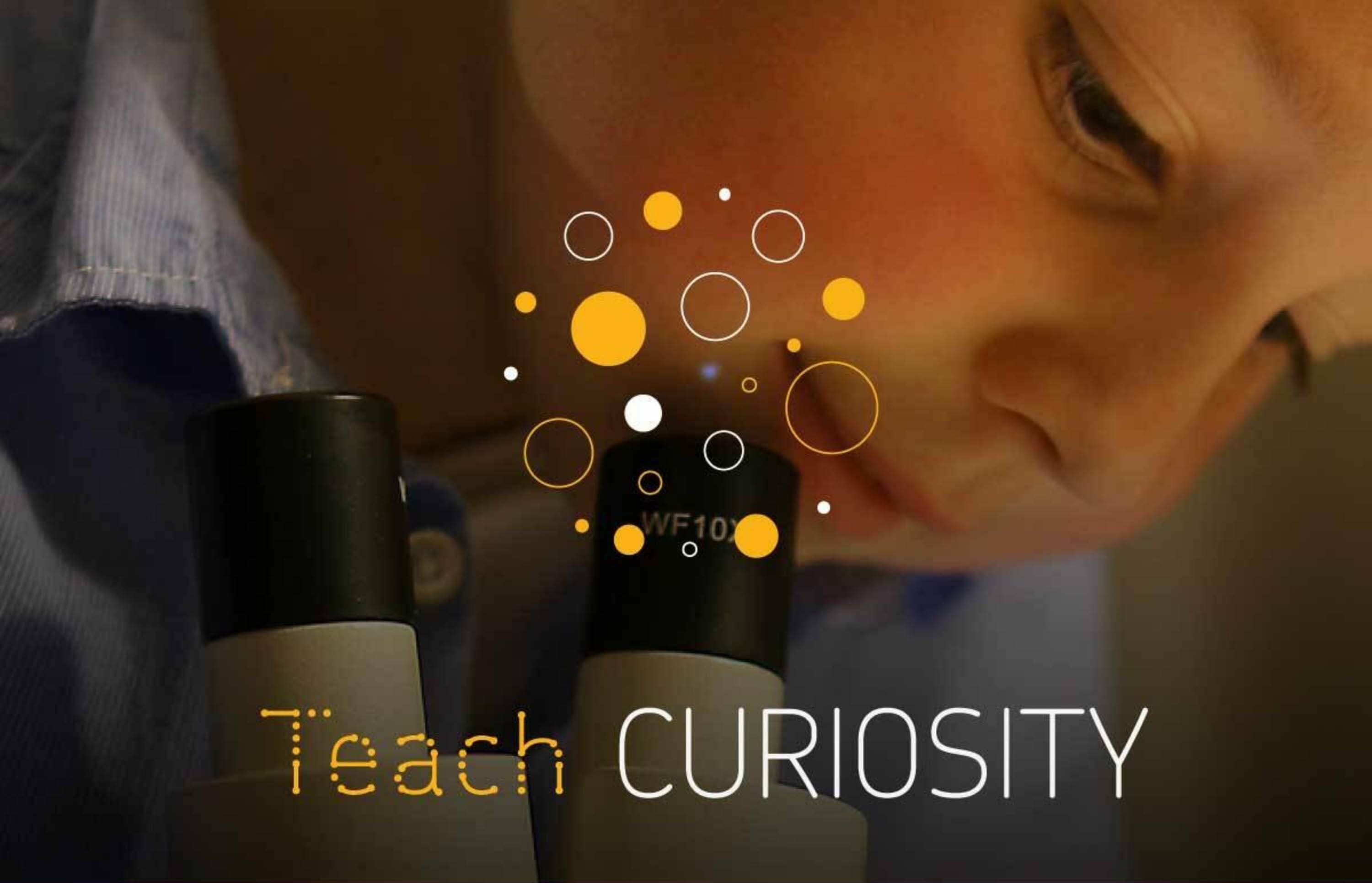 A close-up of a child looking into a microscope, with the words "Teach CURIOSITY" overlaid on the image. The text is decorated with various orange and white circles of different sizes.