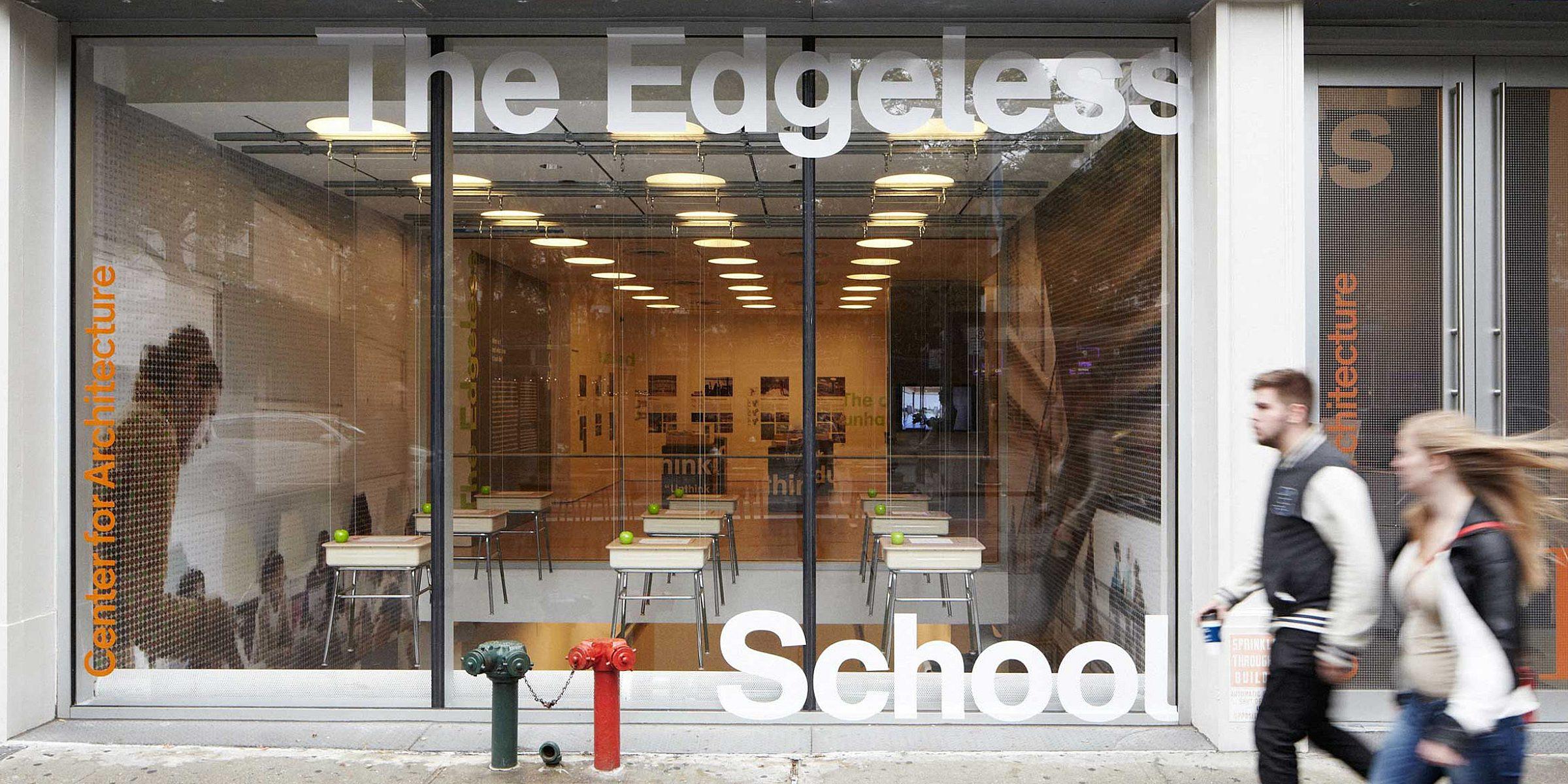 A street view of The Edgeless School, housed in a glass-front building with visible classrooms inside. The signage on the window reads "The Edgeless School" and includes the name "Center for Architecture." Two people walk past the building.