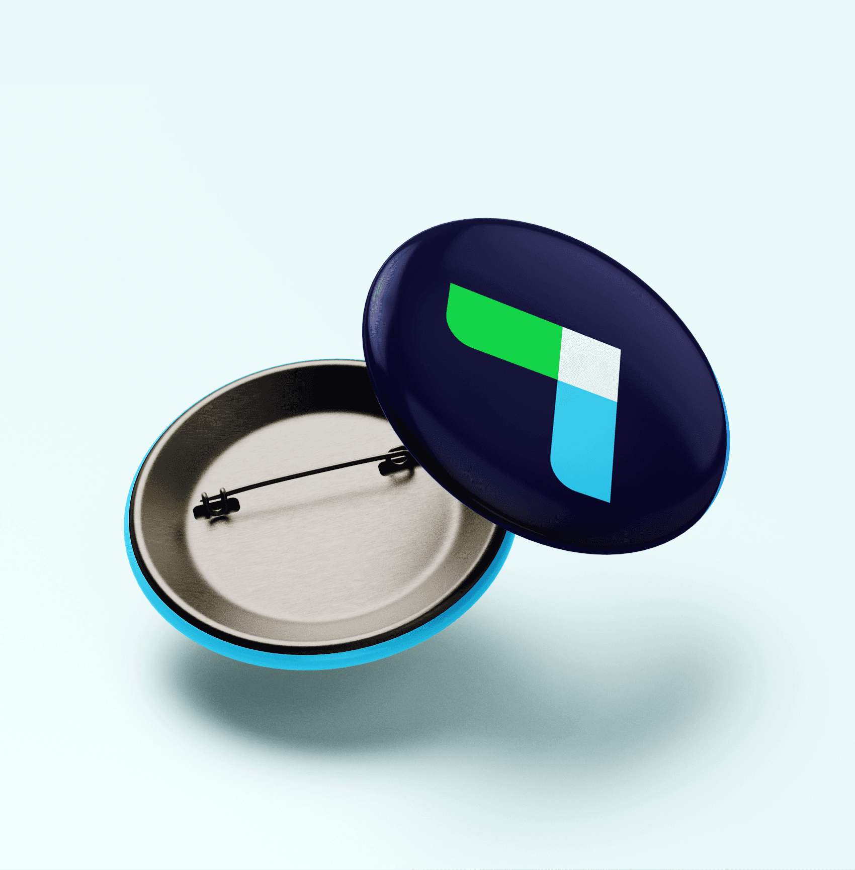 A round, metallic pin badge with a clasp is displayed open. The front of the badge is navy blue with a geometric logo in white, green, and blue shapes, resembling an abstract arrow. The badge is set against a light blue background.