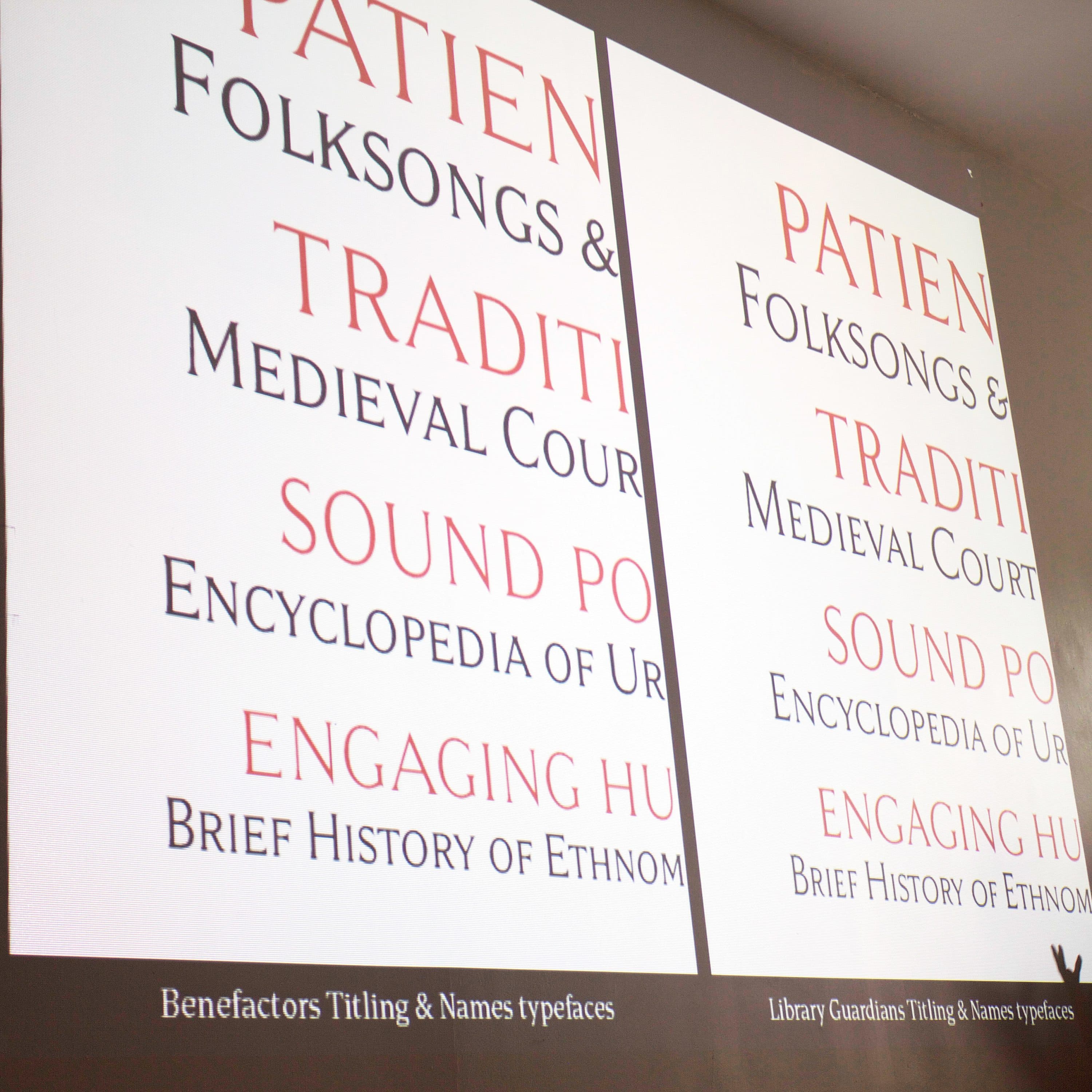 A person stands next to a large projected display showing a comparison of different typographies. The screen features various text phrases, with emphasis on the words "PATIENT," "TRADITIONS," and "ENGAGING HUM." The typefaces compared are "Benefactors Titling & Names" and "Literary Guardians Titling & Names.