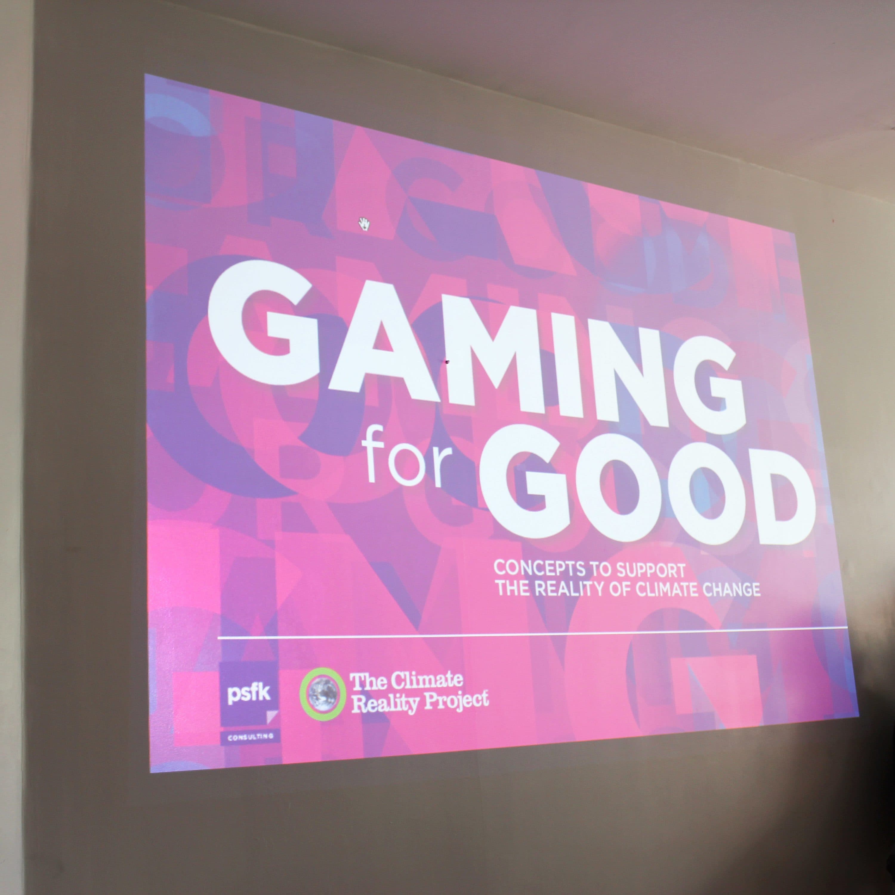 A man sits in a room next to a large presentation screen displaying the title "Gaming for Good" with the subtitle "Concepts to support the reality of climate change." The Climate Reality Project and PSFK logos are shown on the bottom left of the screen.