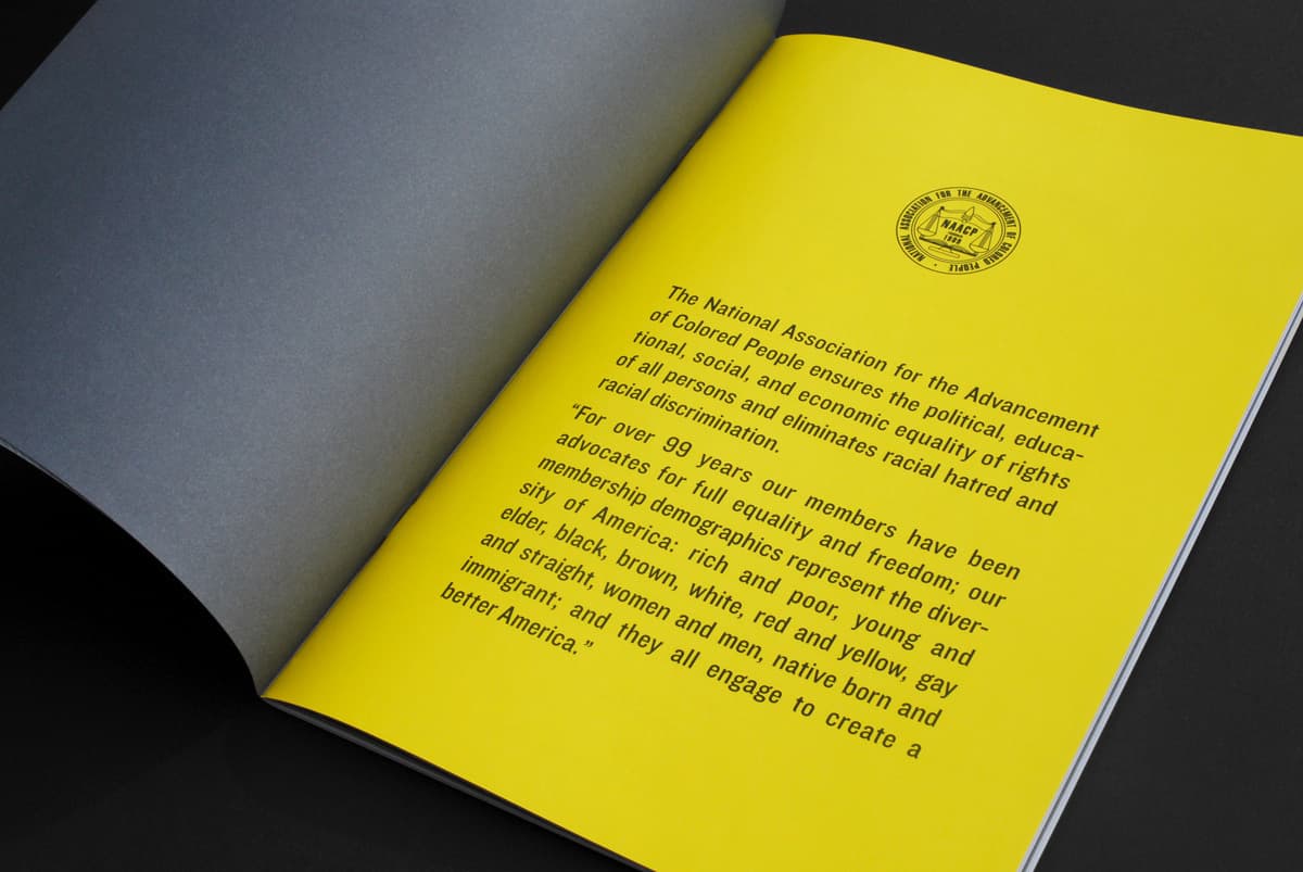 An open book with a black and yellow page. The yellow page features text about the National Association for the Advancement of Colored People, highlighting its commitment to racial justice, and equality. The organization's logo is at the top of the yellow page.