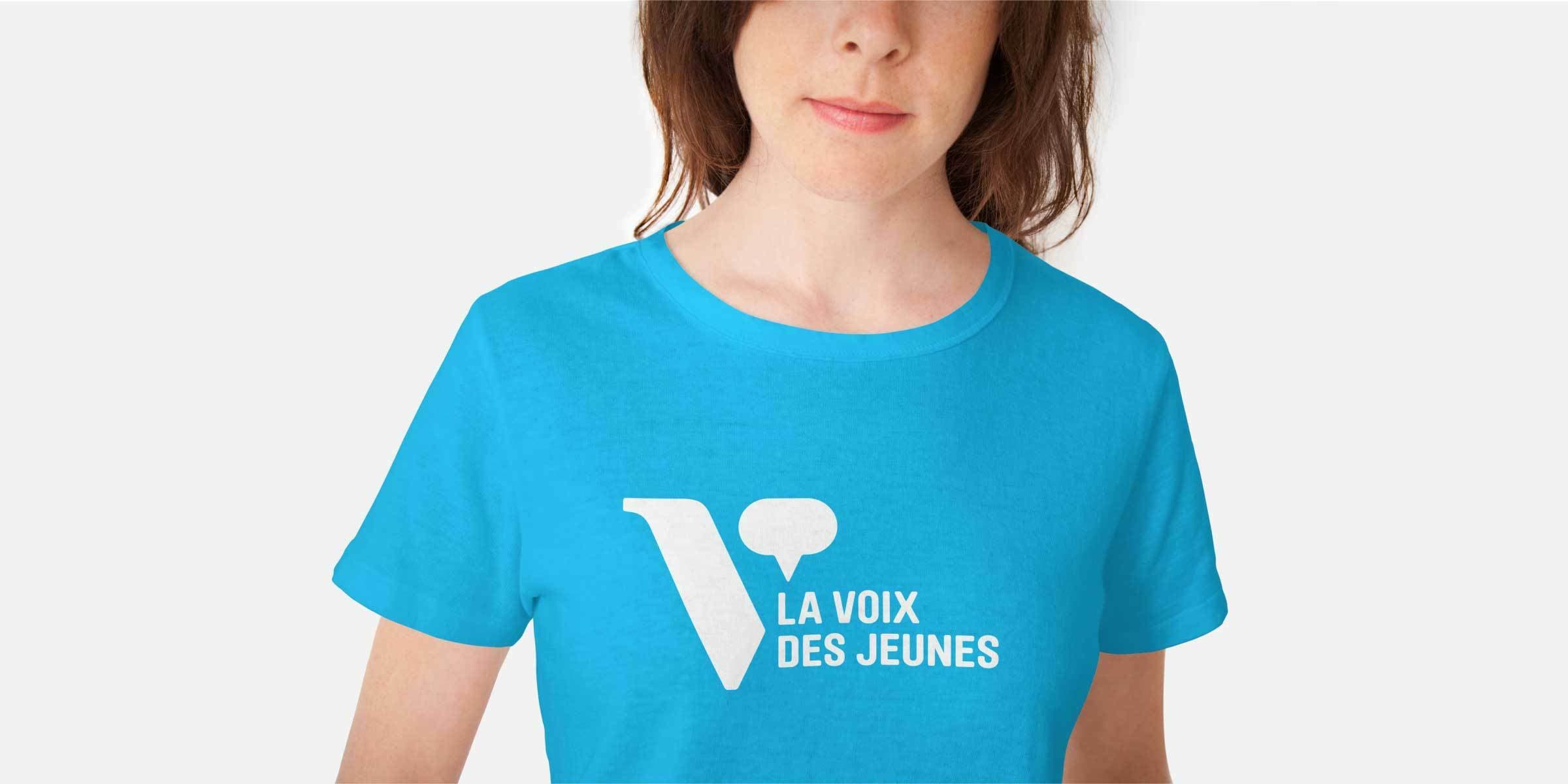 A person wearing a bright blue t-shirt with the text "La Voix des Jeunes" and a large "V" with a speech bubble graphic printed on the front. The background is plain white.